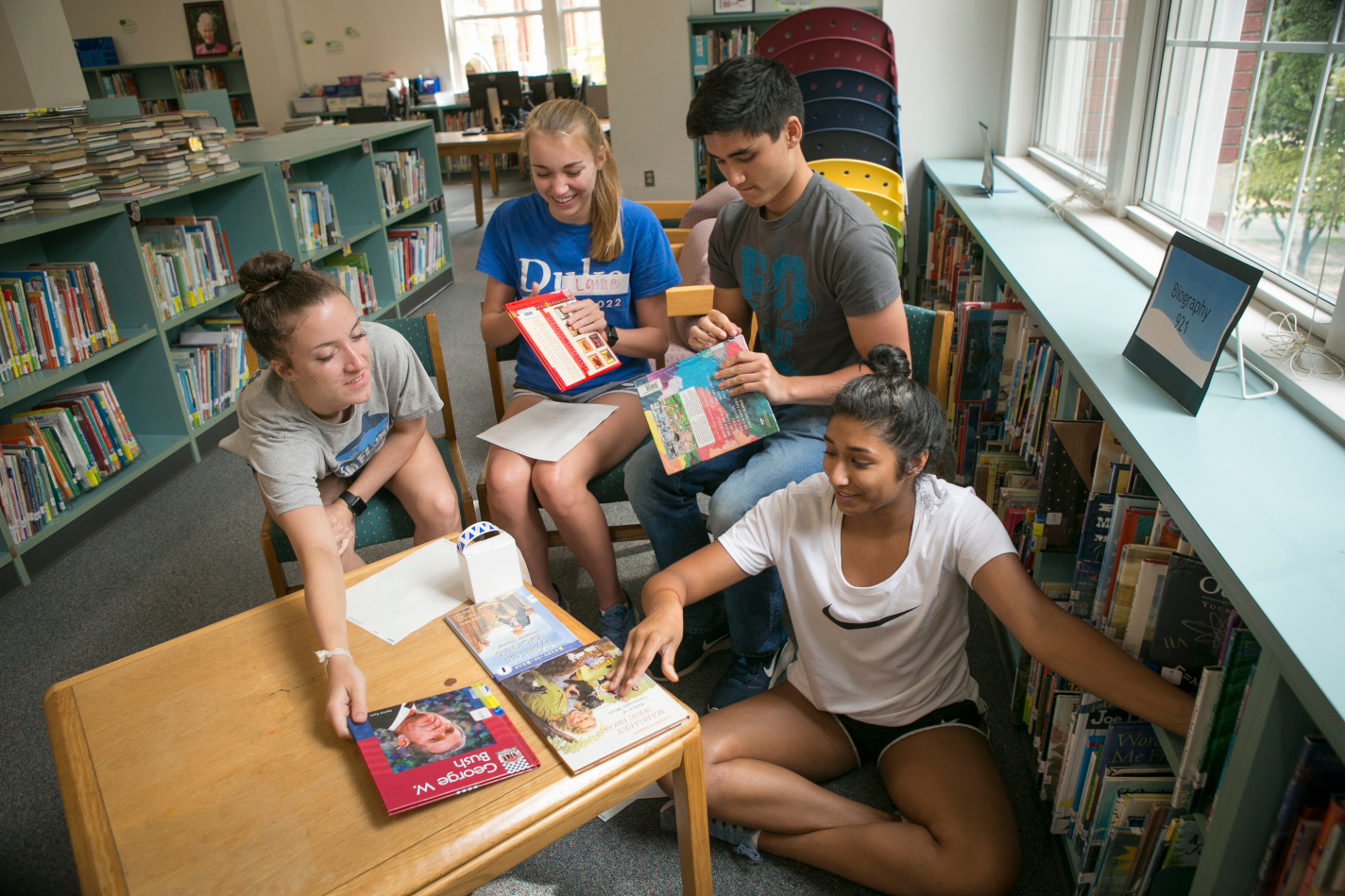 Students in a library talking about books.