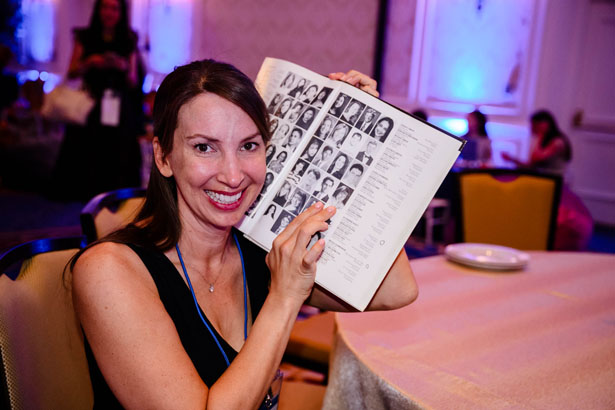 Woman posing with yearbook at reunions