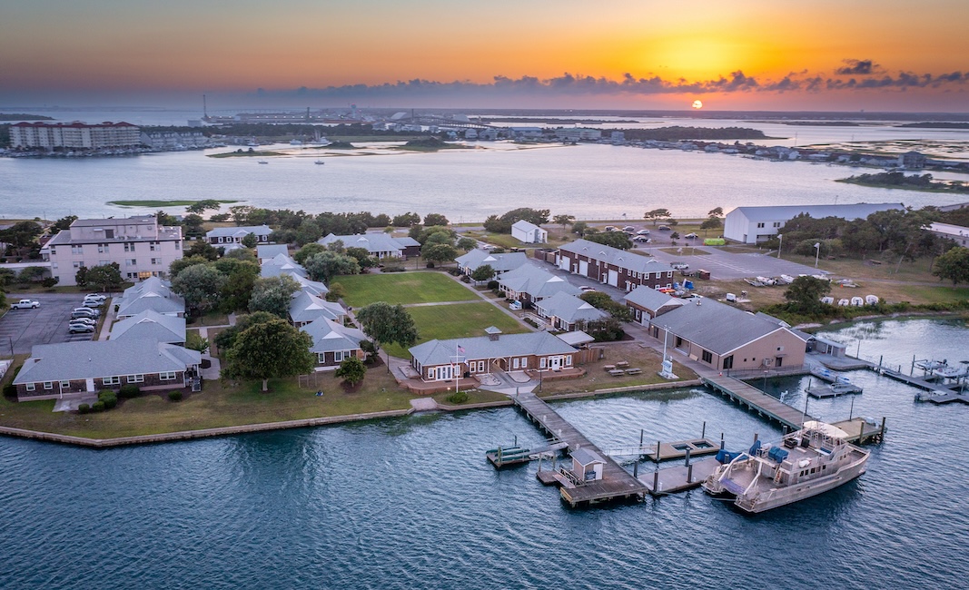 Aerial view of buildings at sunset with water in front and behind.