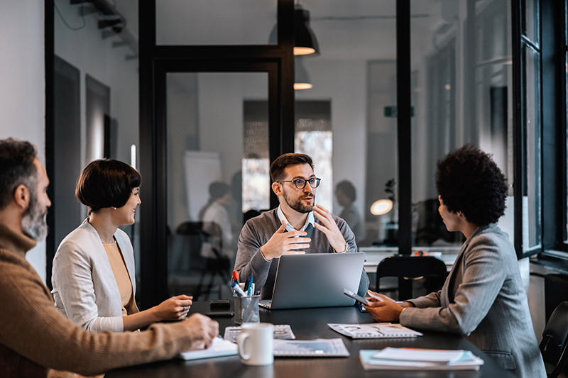 Group of people at a table in office casual clothes talking. 