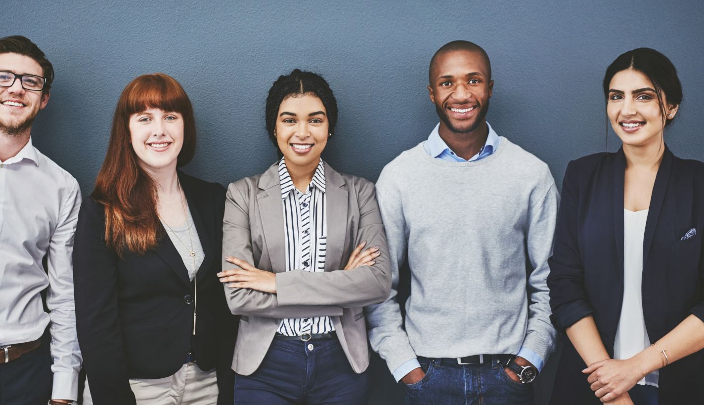 Five people in office casual clothes smiling at the camera.