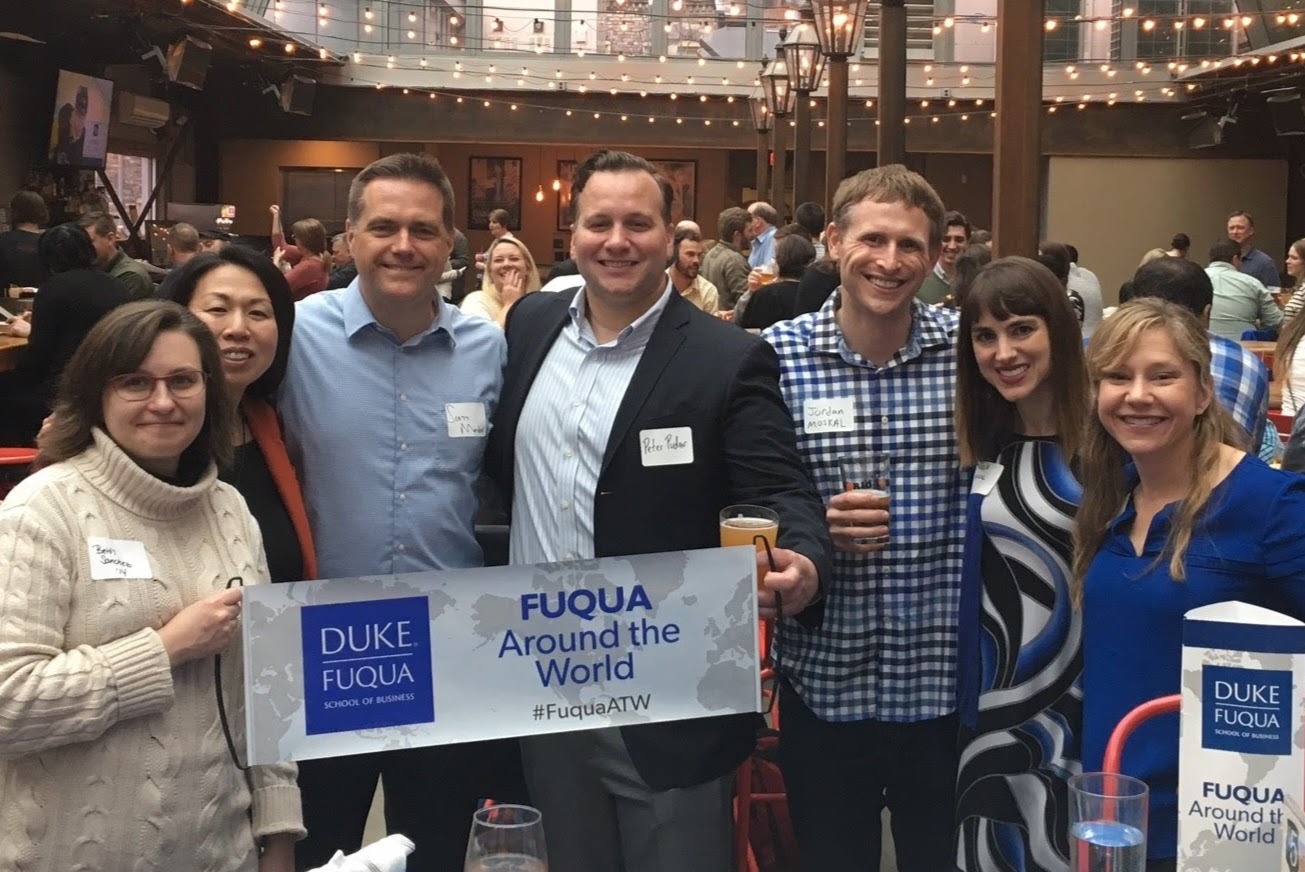 A group of Fuqua Around the World participants having a good time at the event and holding Fuqua signs